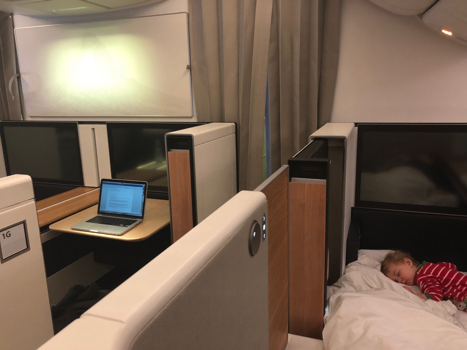 a child sleeping in a bed with a laptop on it