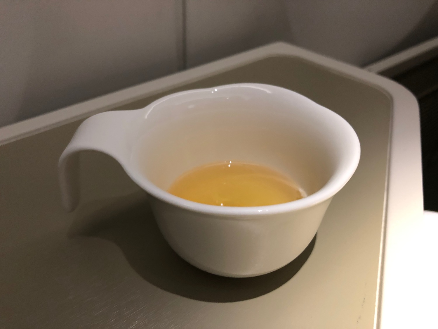 a white cup with a handle and a yellow liquid in it