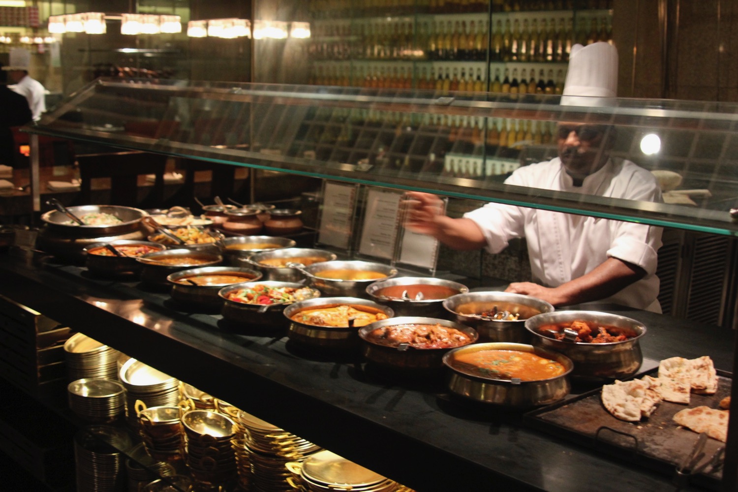 a chef standing behind a counter with many bowls of food