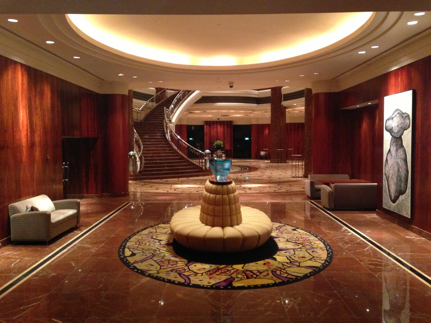 a large lobby with a circular staircase and a large vase on a round rug