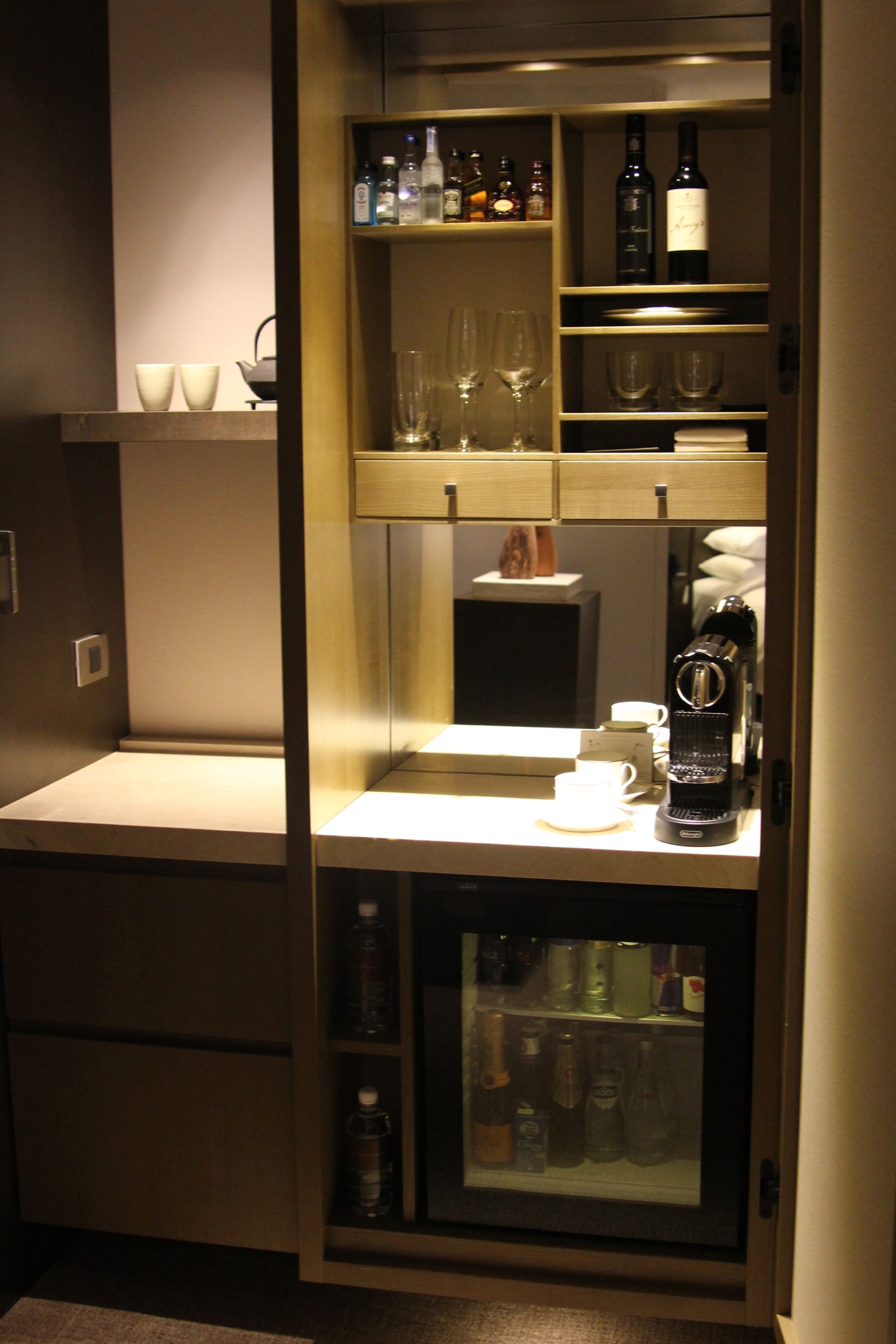 a cabinet with wine glasses and a coffee machine