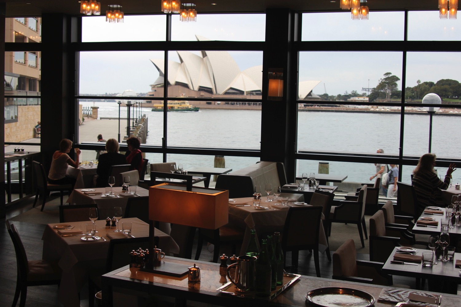 a restaurant with a view of the opera house and water