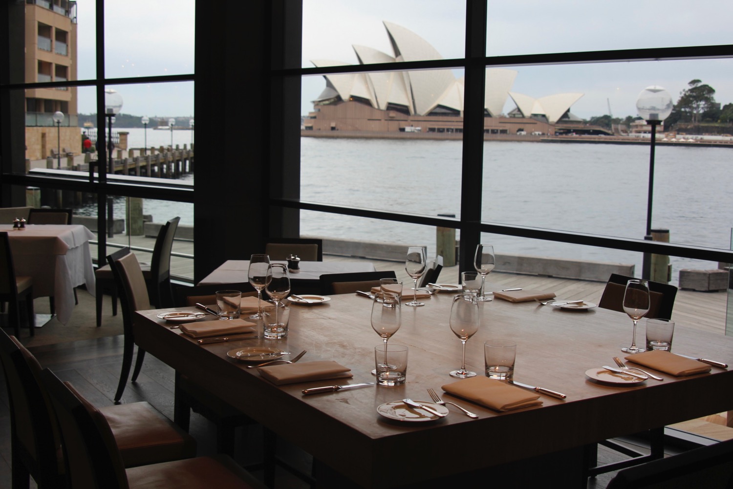 a table set for a dinner with a view of the opera house and water