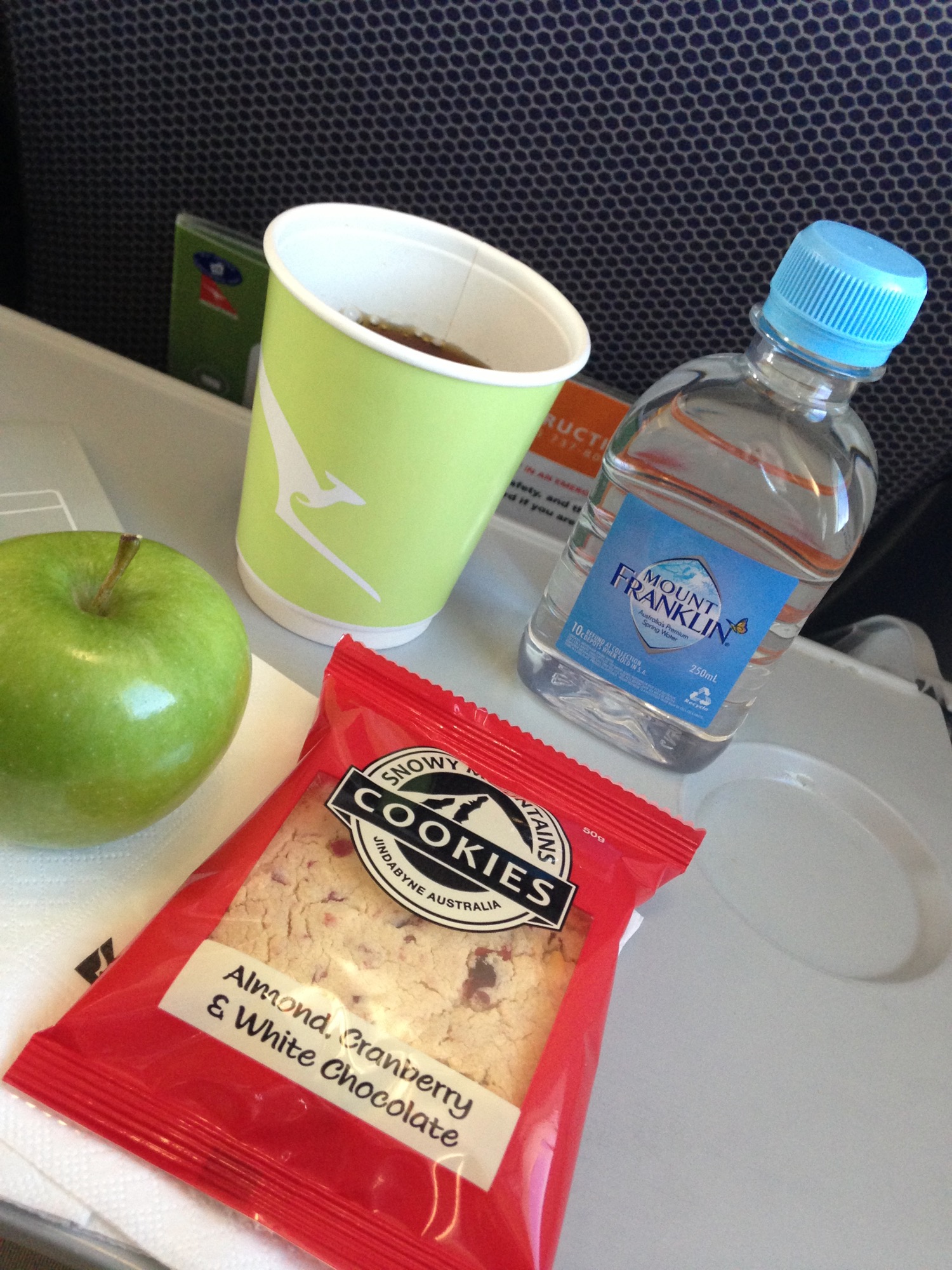 a green apple and a bag of cookies next to a green cup of water