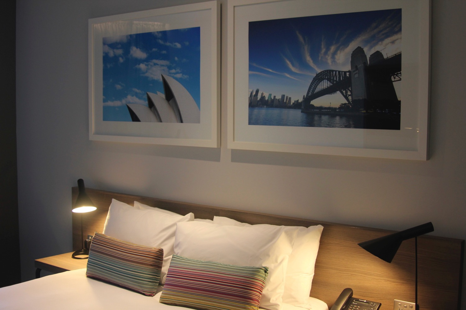 a bed with pillows and a lamp next to a picture on the wall