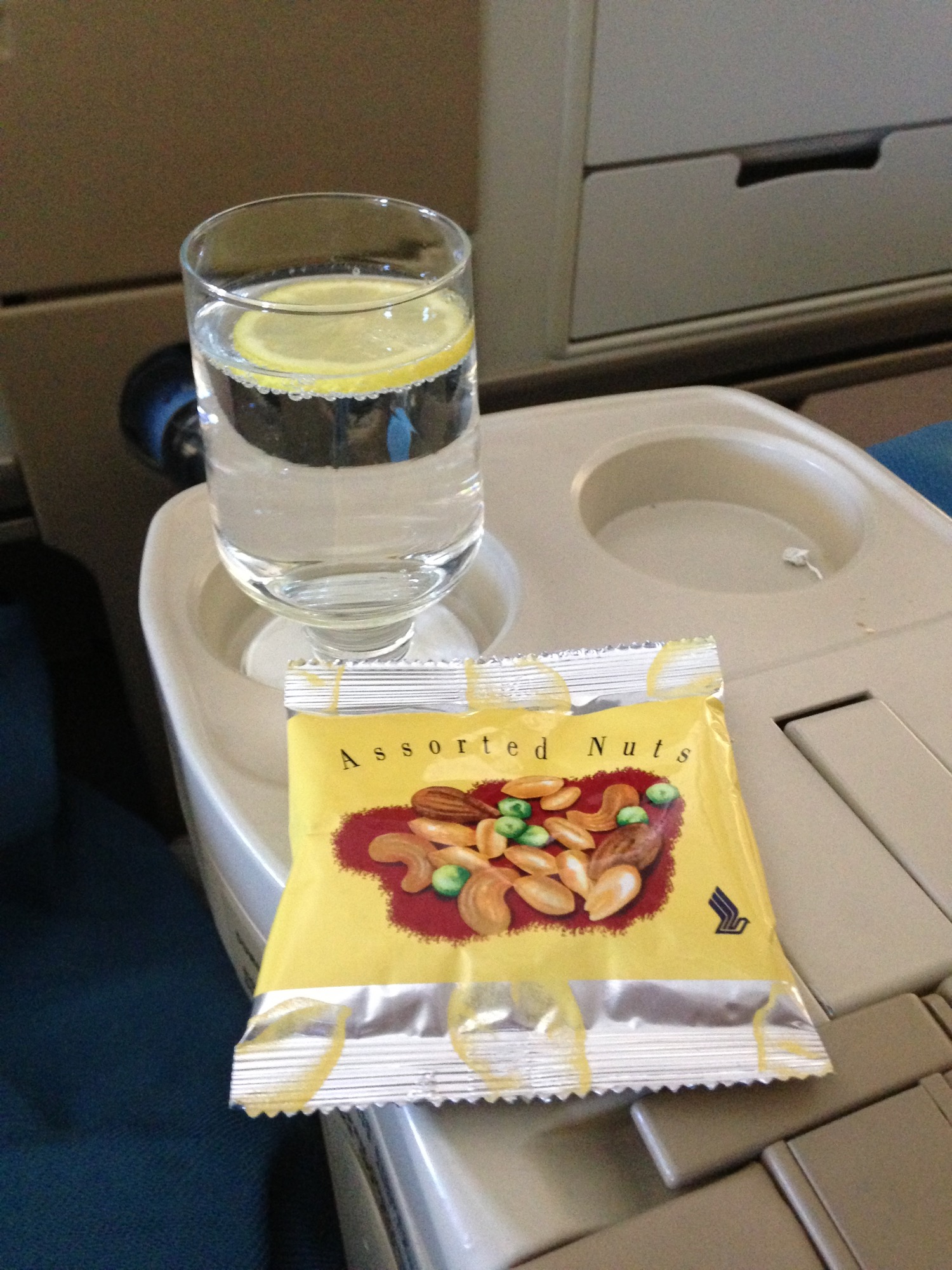 a glass of water and a bag of nuts on a tray