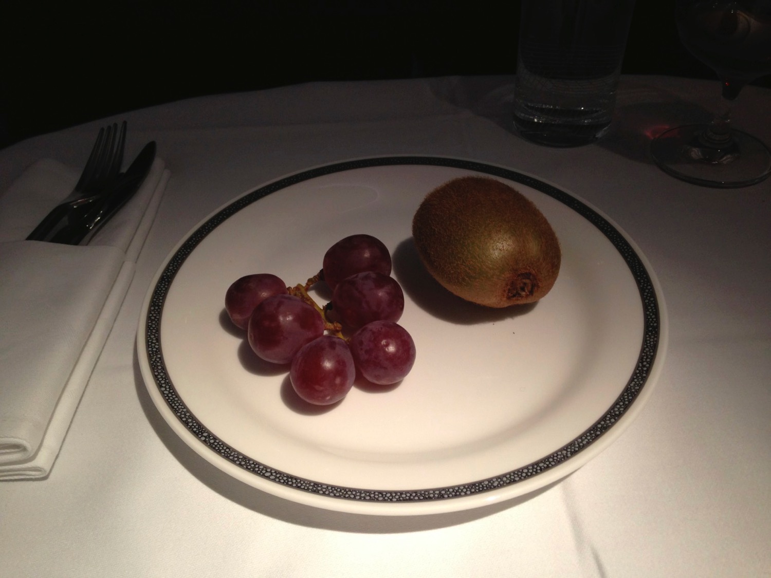 a plate with grapes and a kiwi on it