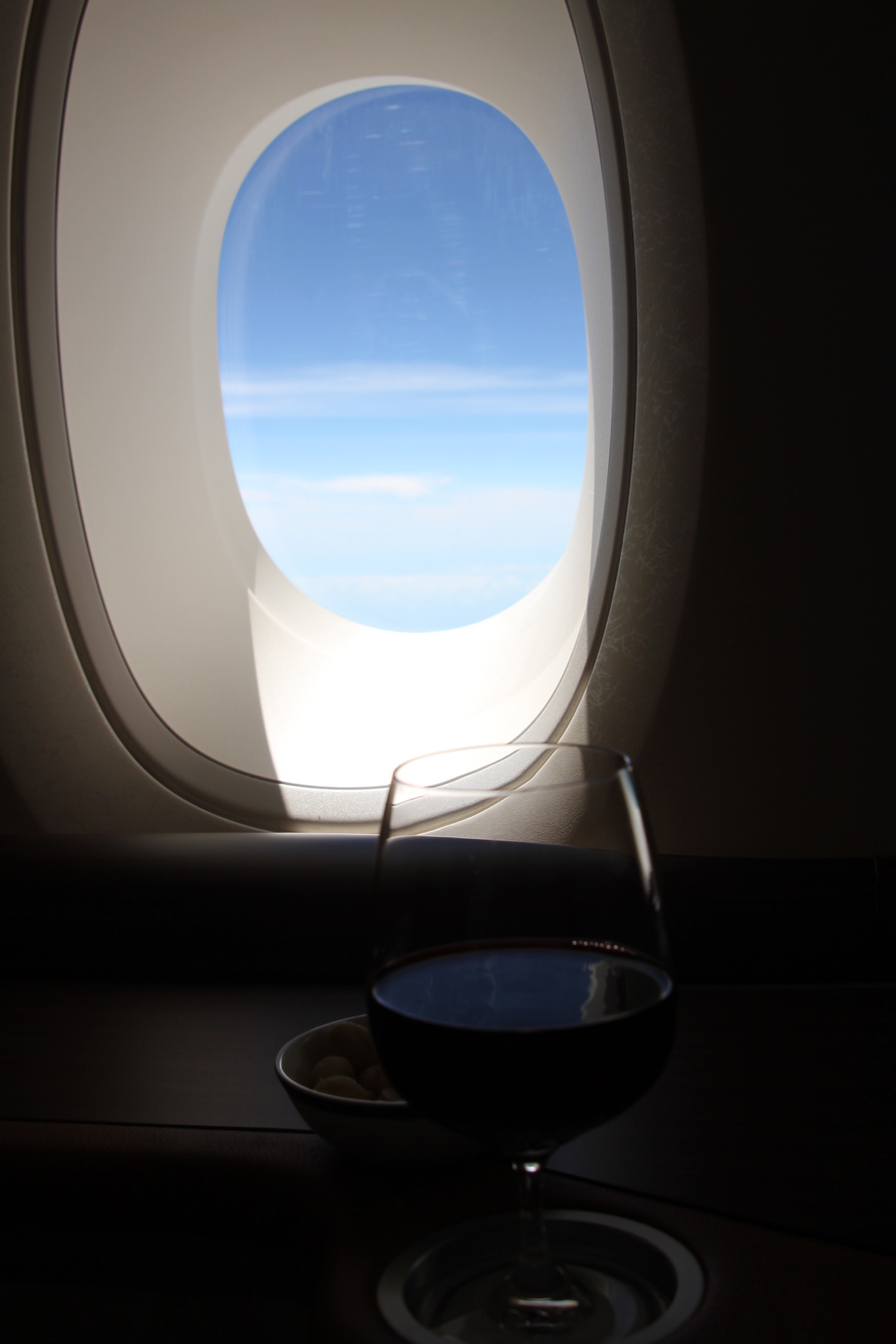 a glass of wine and a bowl of food on a table with a window