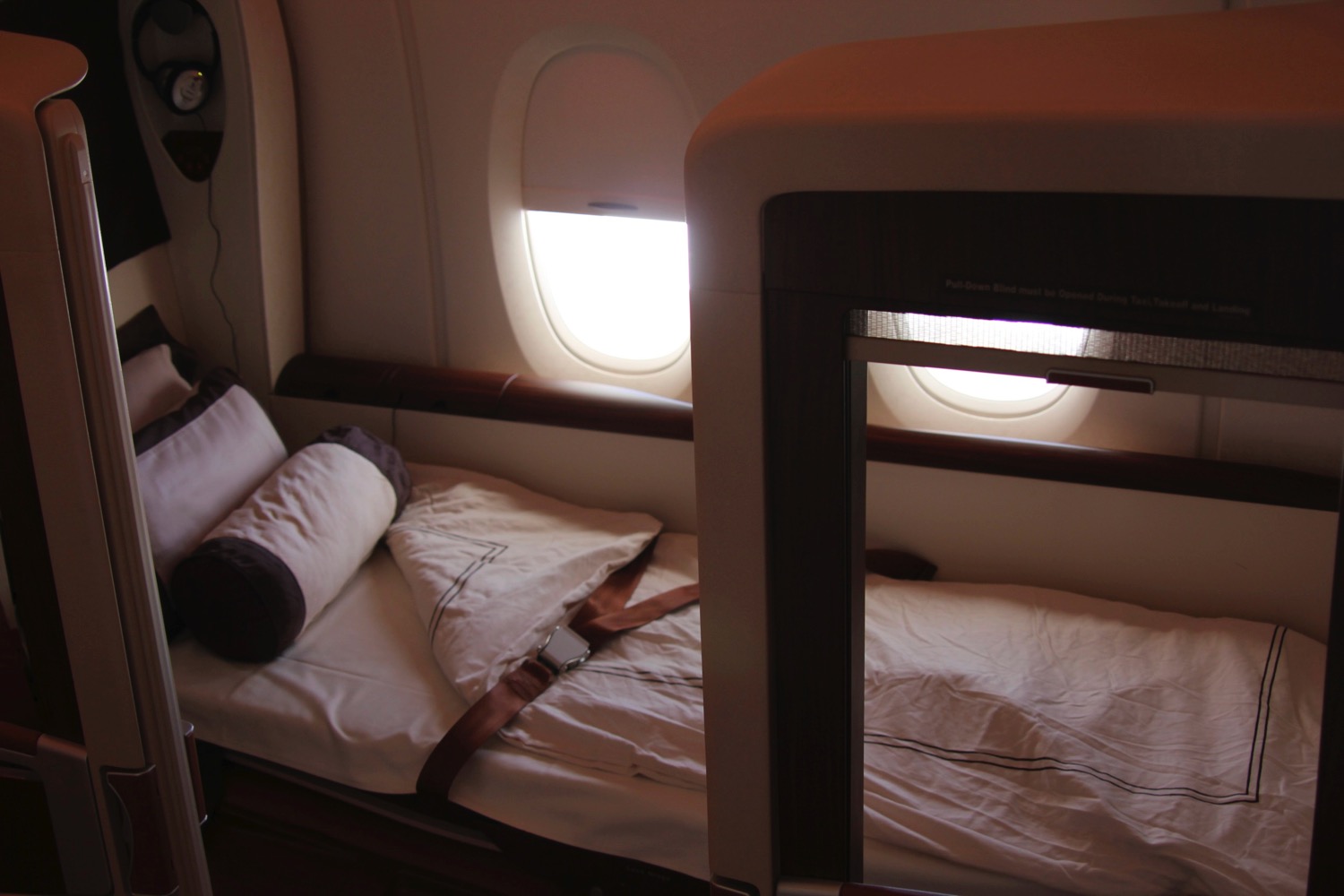 a bed with a seat belt and pillows on a plane