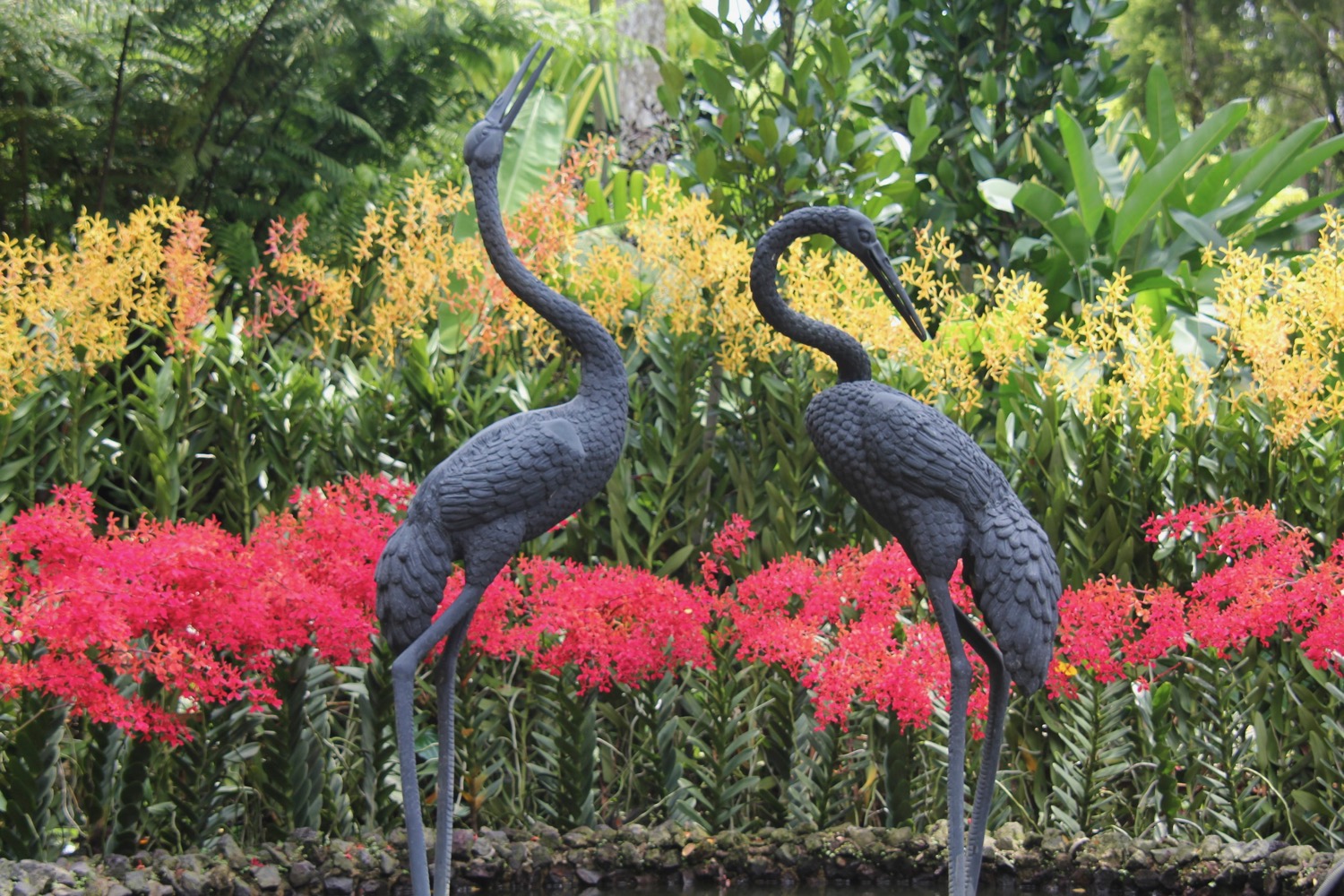 two statues of birds in a garden