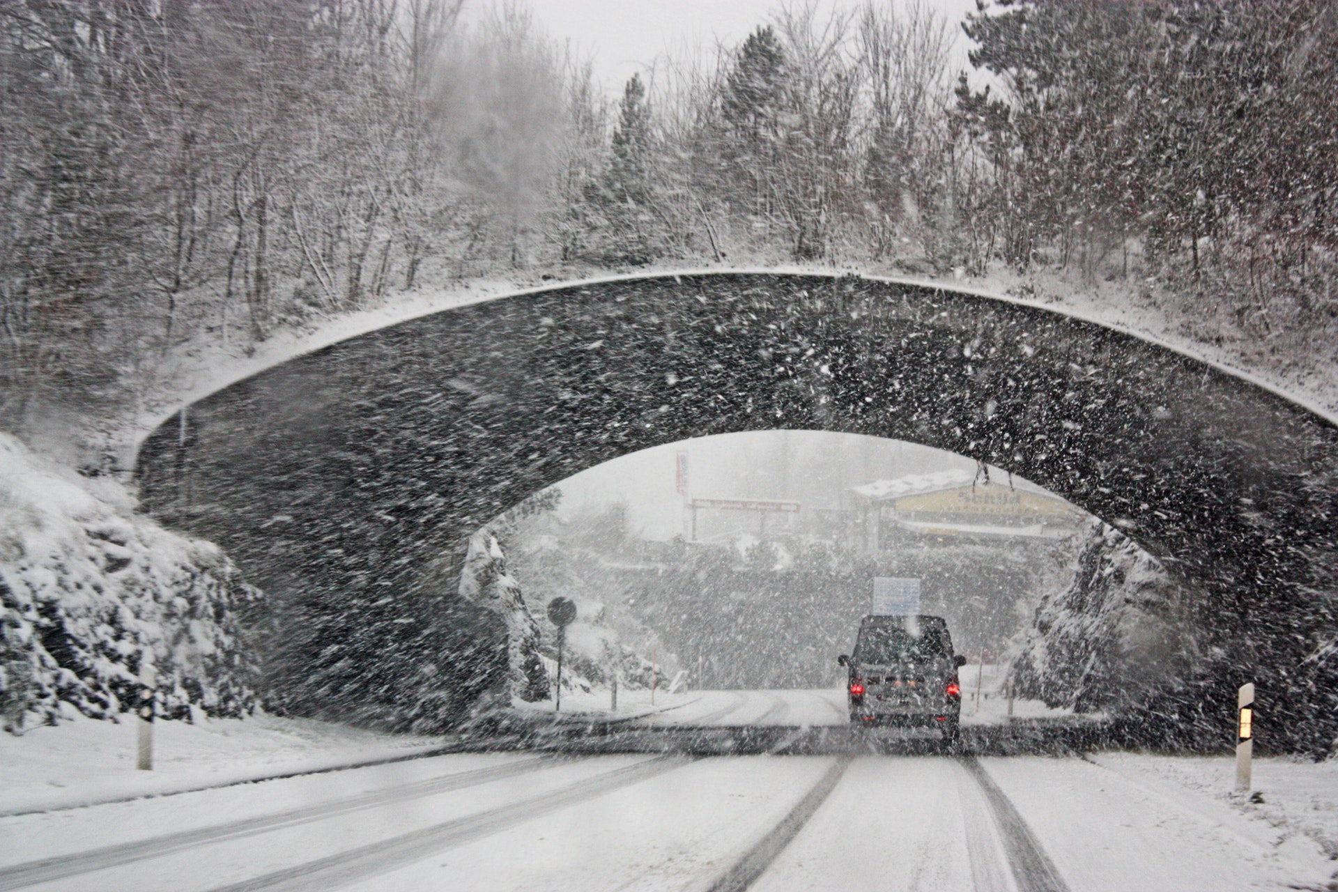 a car driving under a bridge in the snow