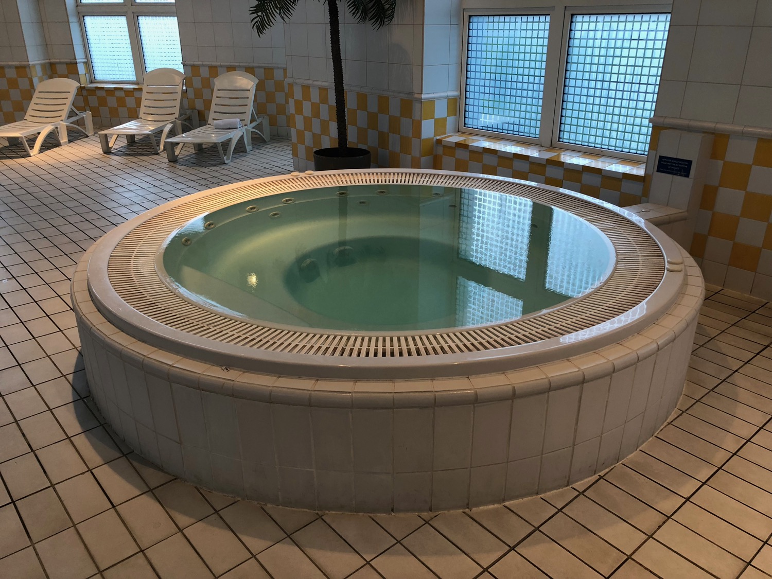 a large round hot tub in a room with yellow and white tiles