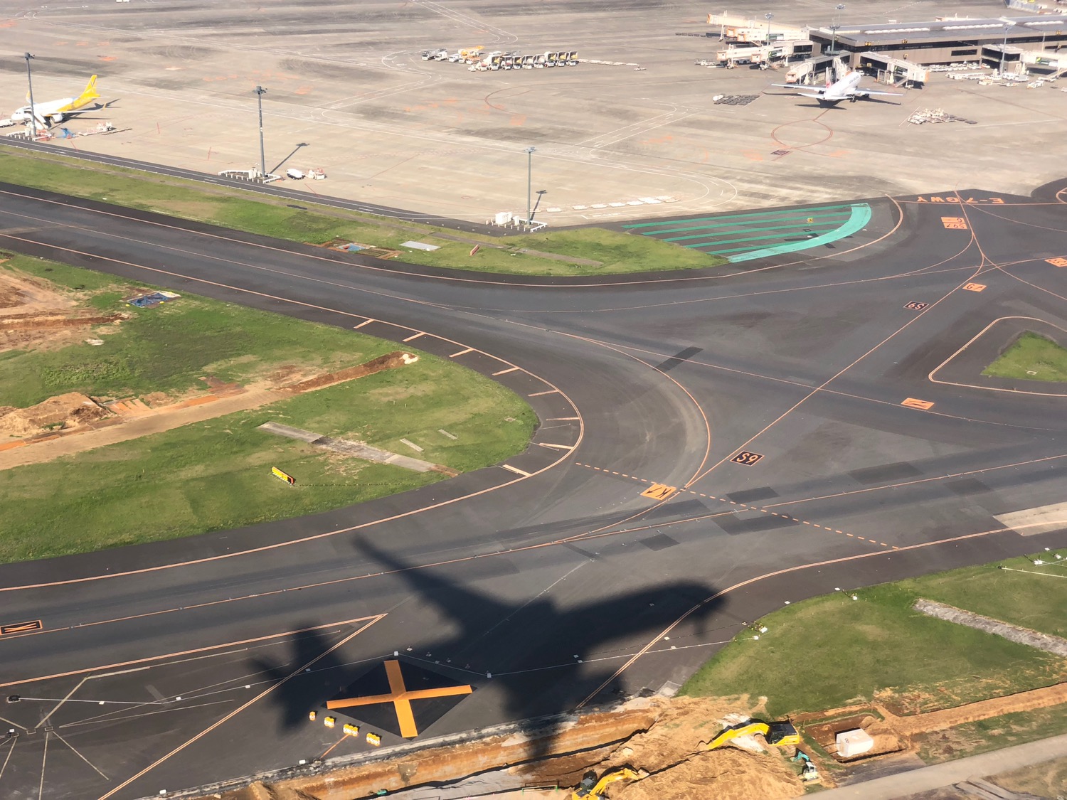 an airport runway with an airplane shadow on the ground