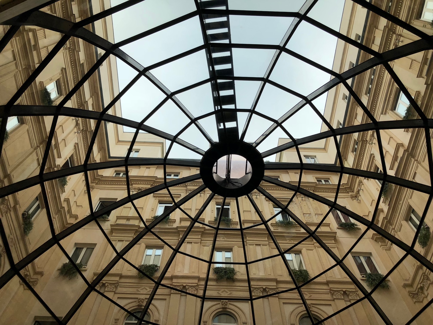 a glass roof with a circular structure with Pont des Arts in the background
