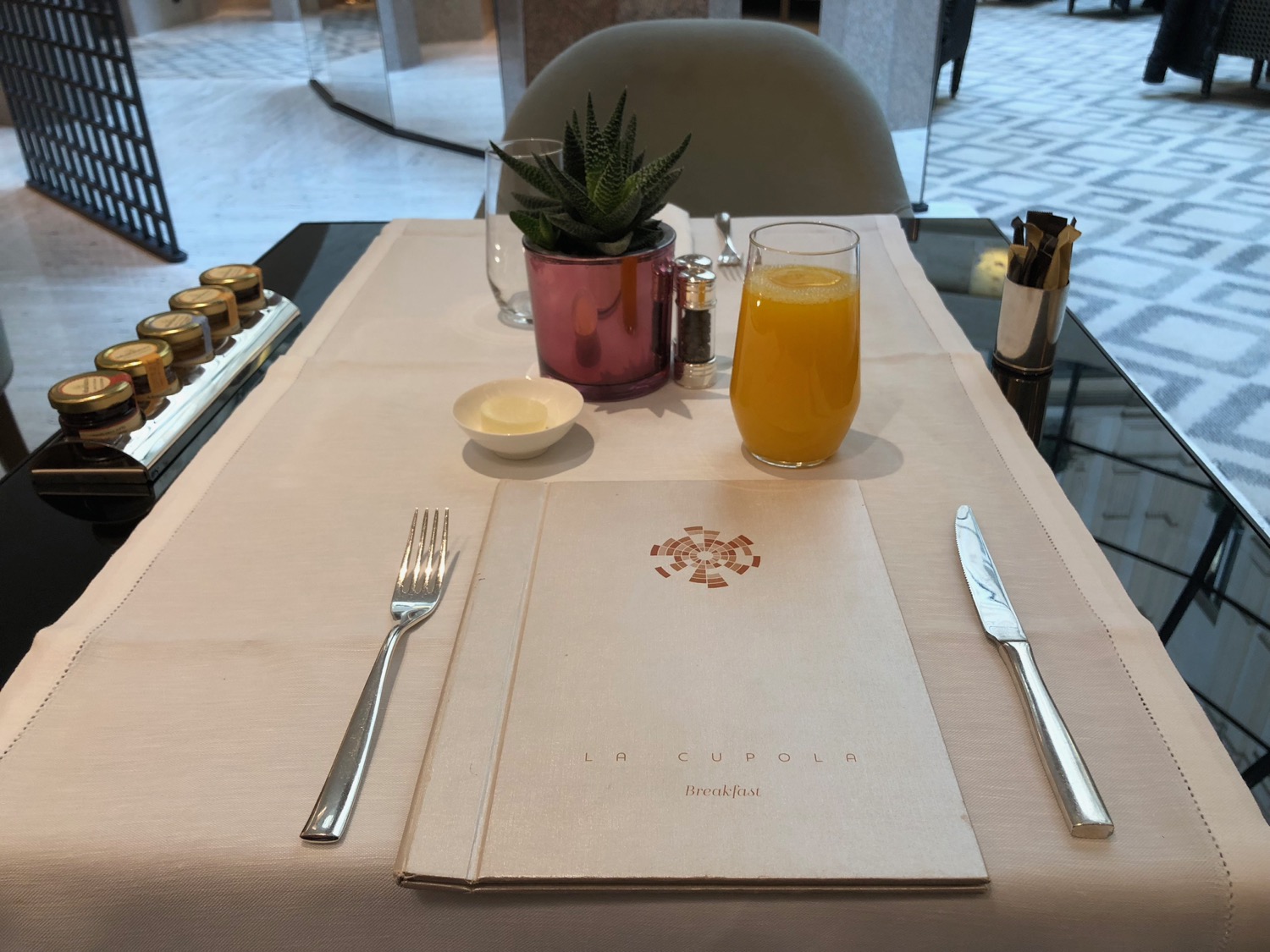 a table with a menu and a glass of juice and a cactus