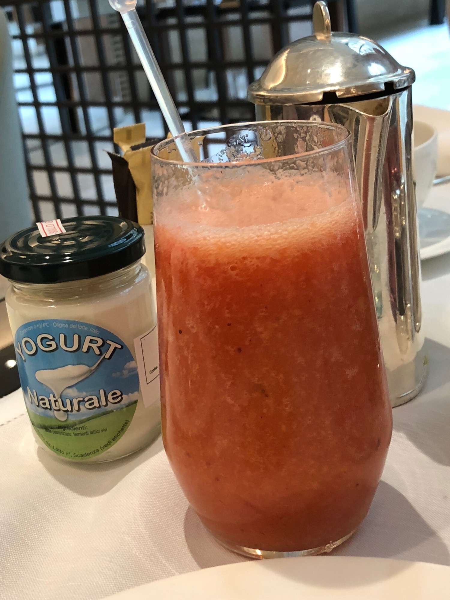 a glass of red liquid next to a jar of yogurt
