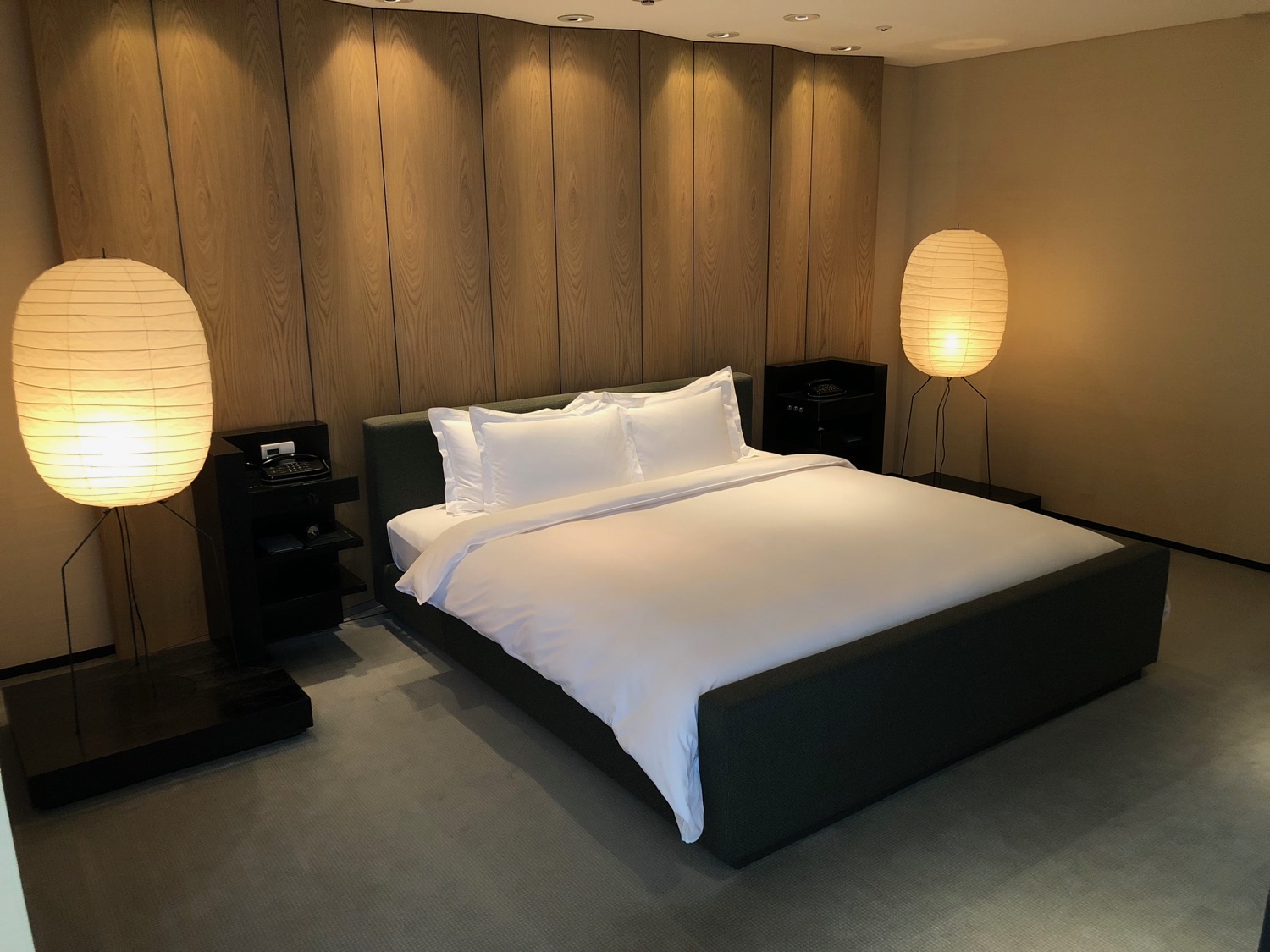 a bed with white sheets and pillows in a room with wood paneled walls