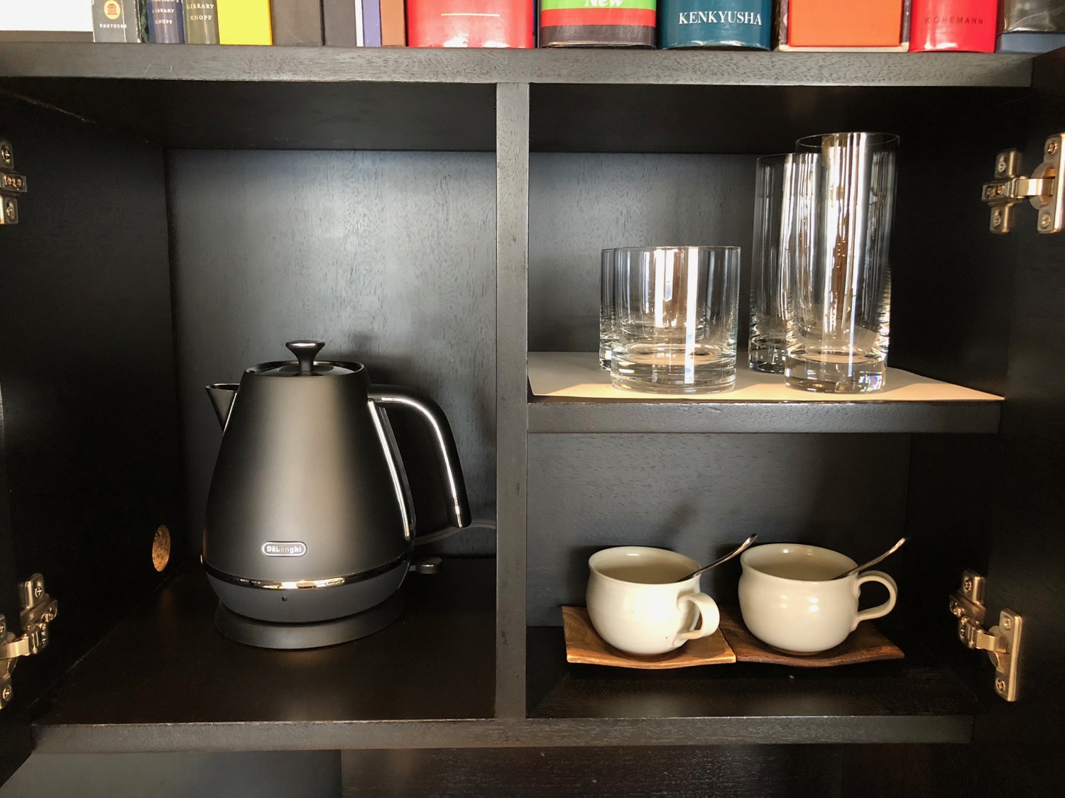 a shelf with a black kettle and cups