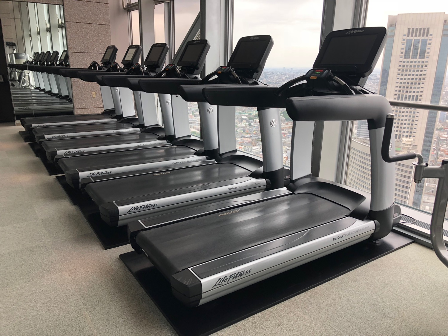 a row of treadmills in a room with windows