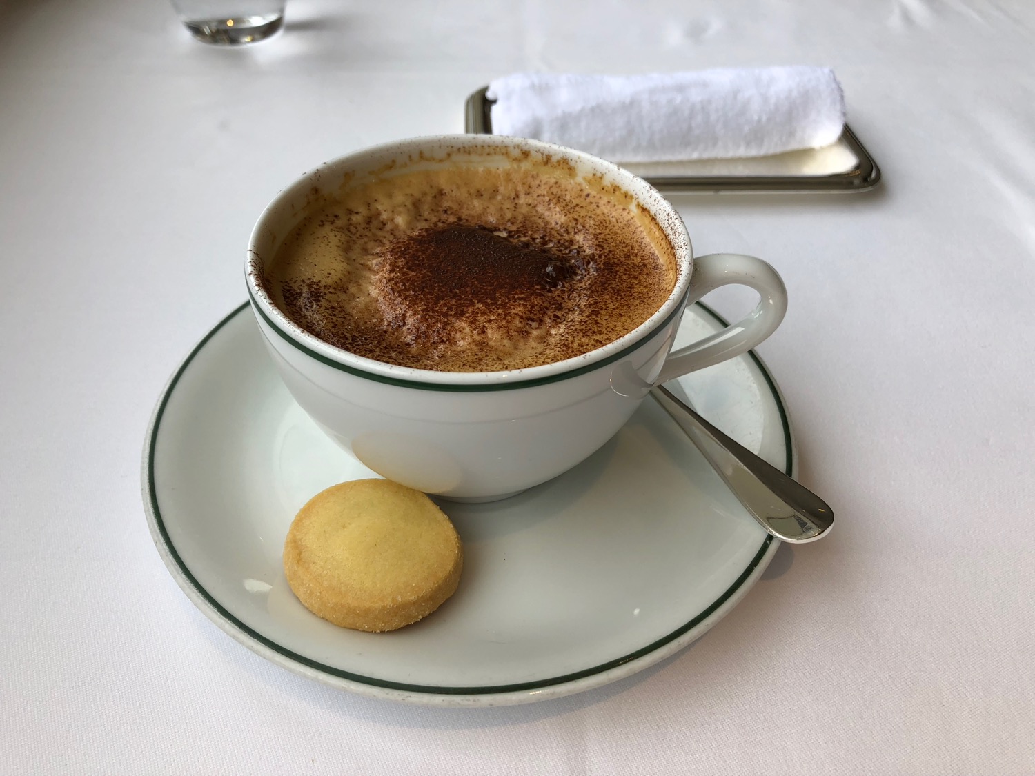 a cup of coffee with a cookie on a plate