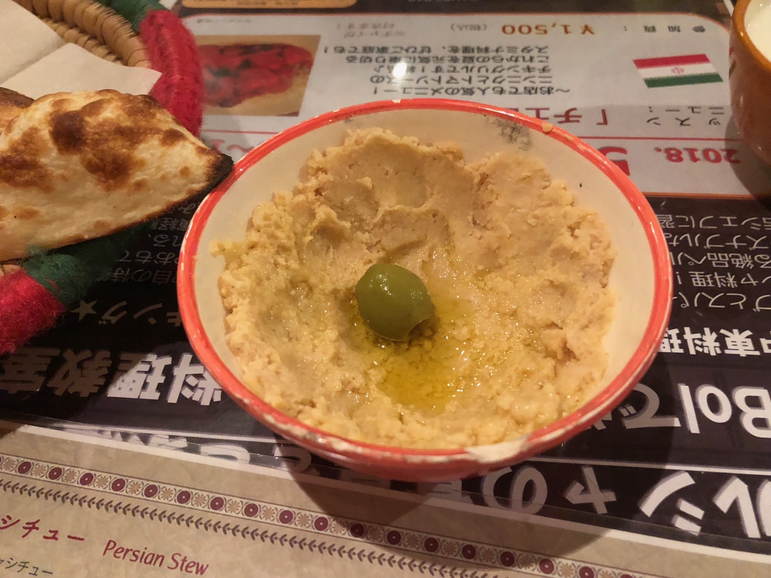 a bowl of hummus with a green olive in it