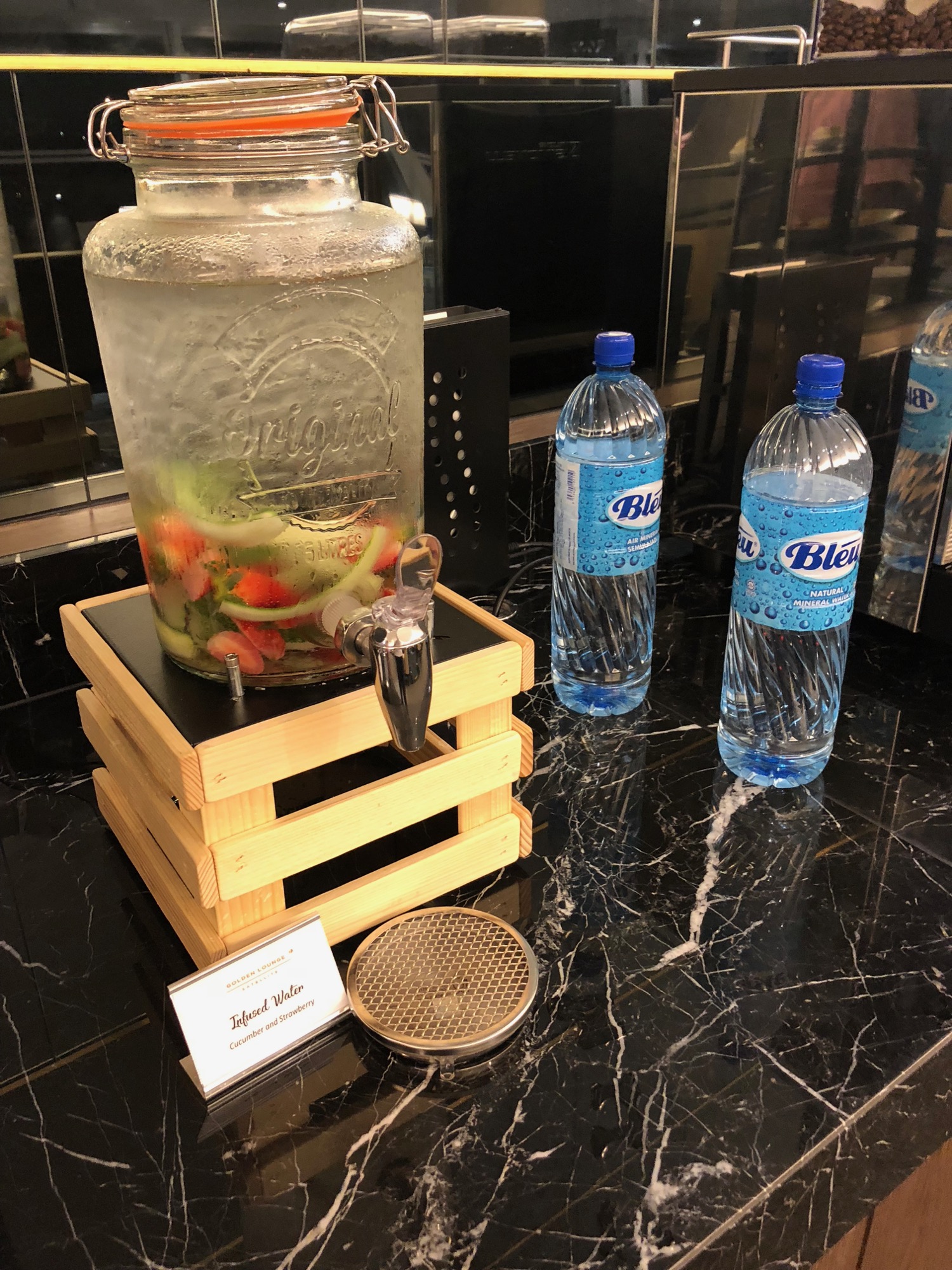 a water dispenser with fruit on a wooden box next to two bottles of water