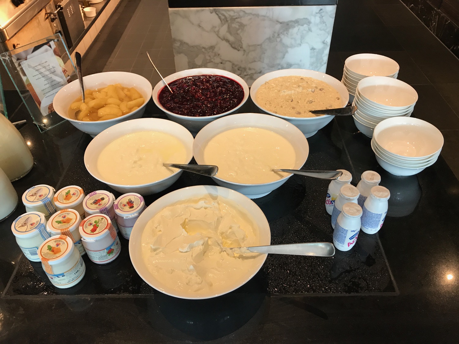 a table with bowls of food and containers of yogurt