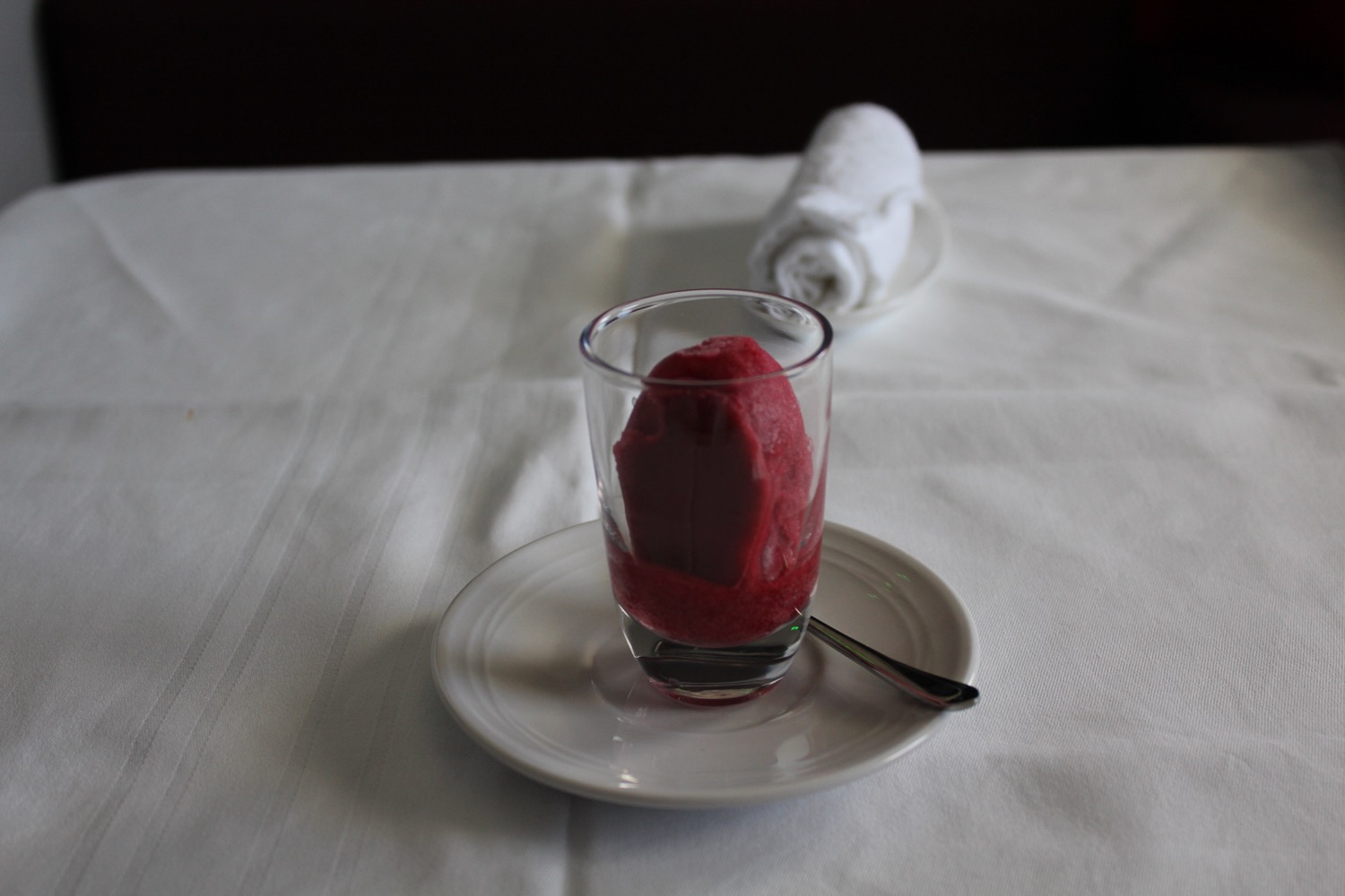 a glass with a red substance on a plate with a white towel