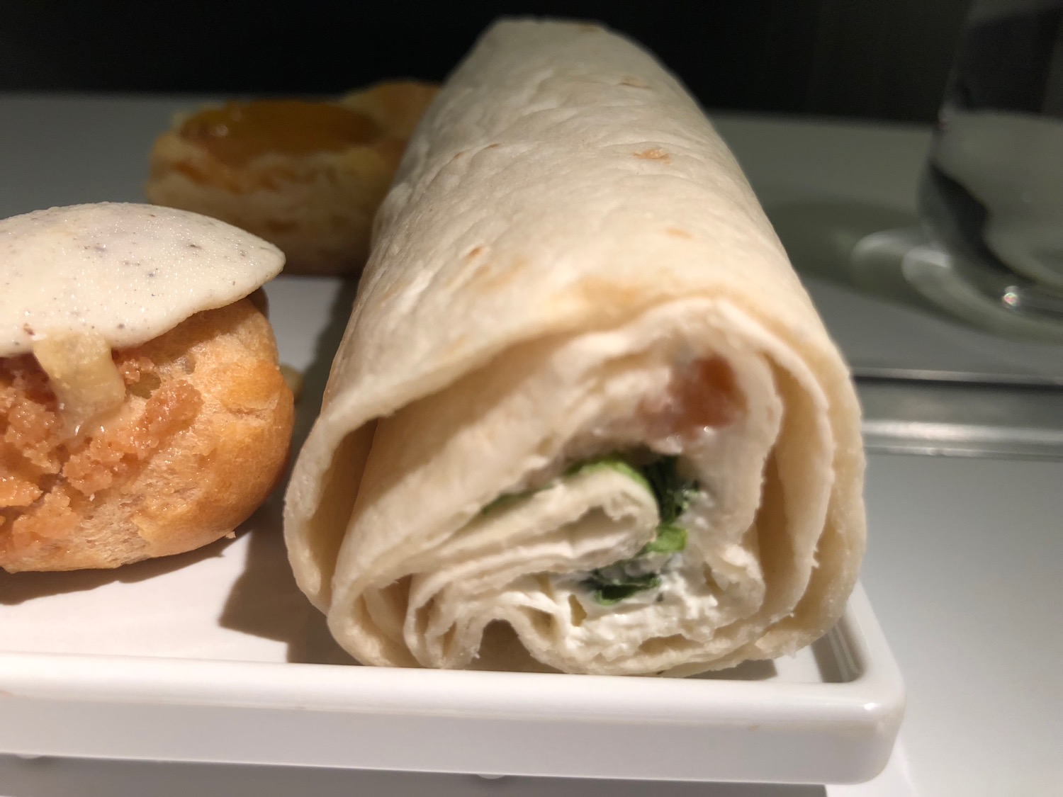 a roll of tortilla with cream cheese and greens