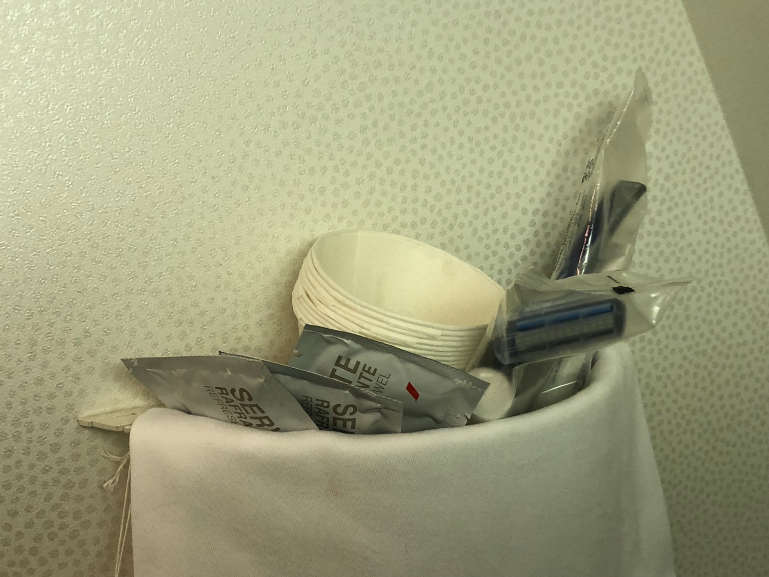 a white towel with a bag of disposable cups and razor