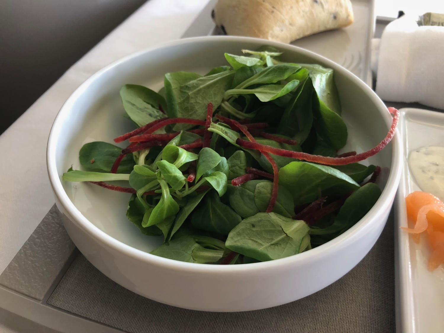 a bowl of salad with a piece of bread
