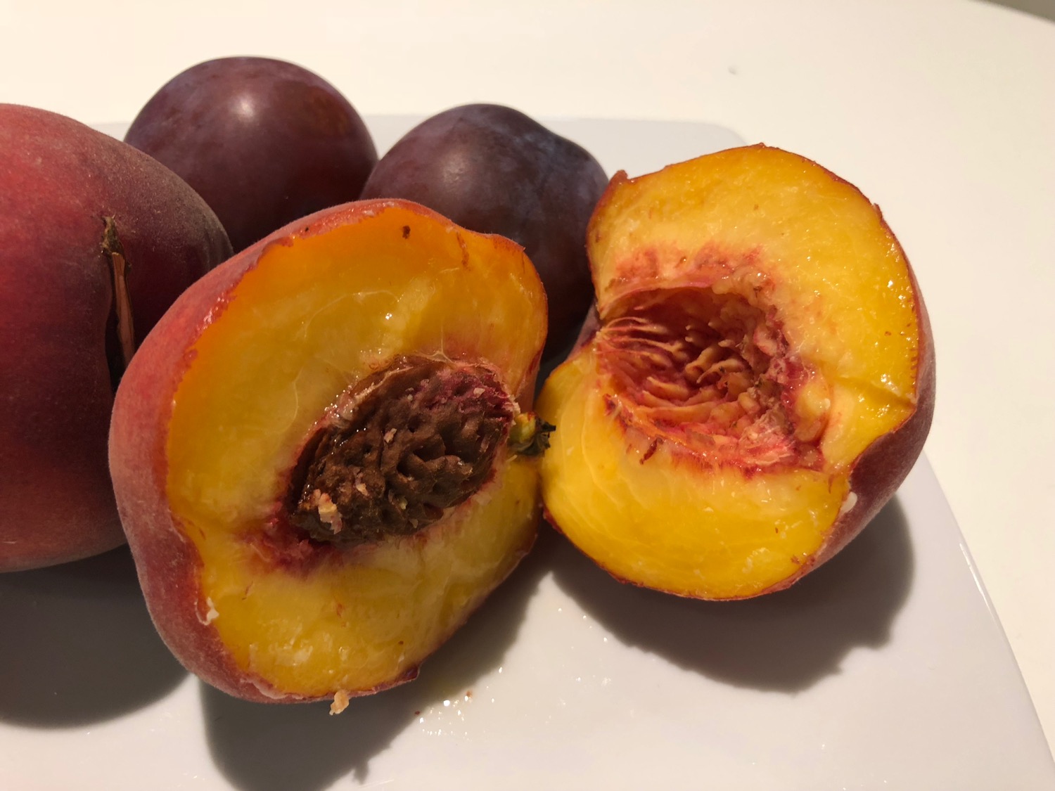 a peach cut in half and a few plums