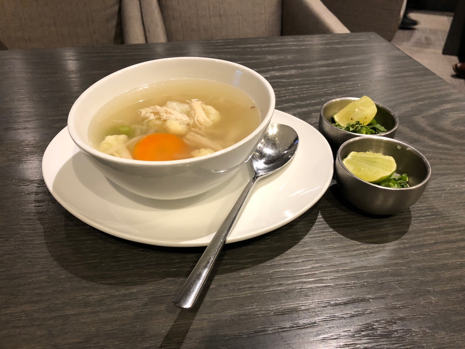 a bowl of soup with a spoon and small bowls of vegetables on a table