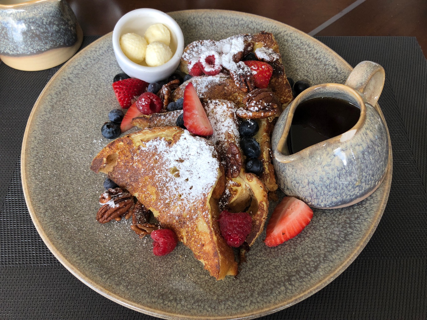 a plate of french toast with berries and nuts