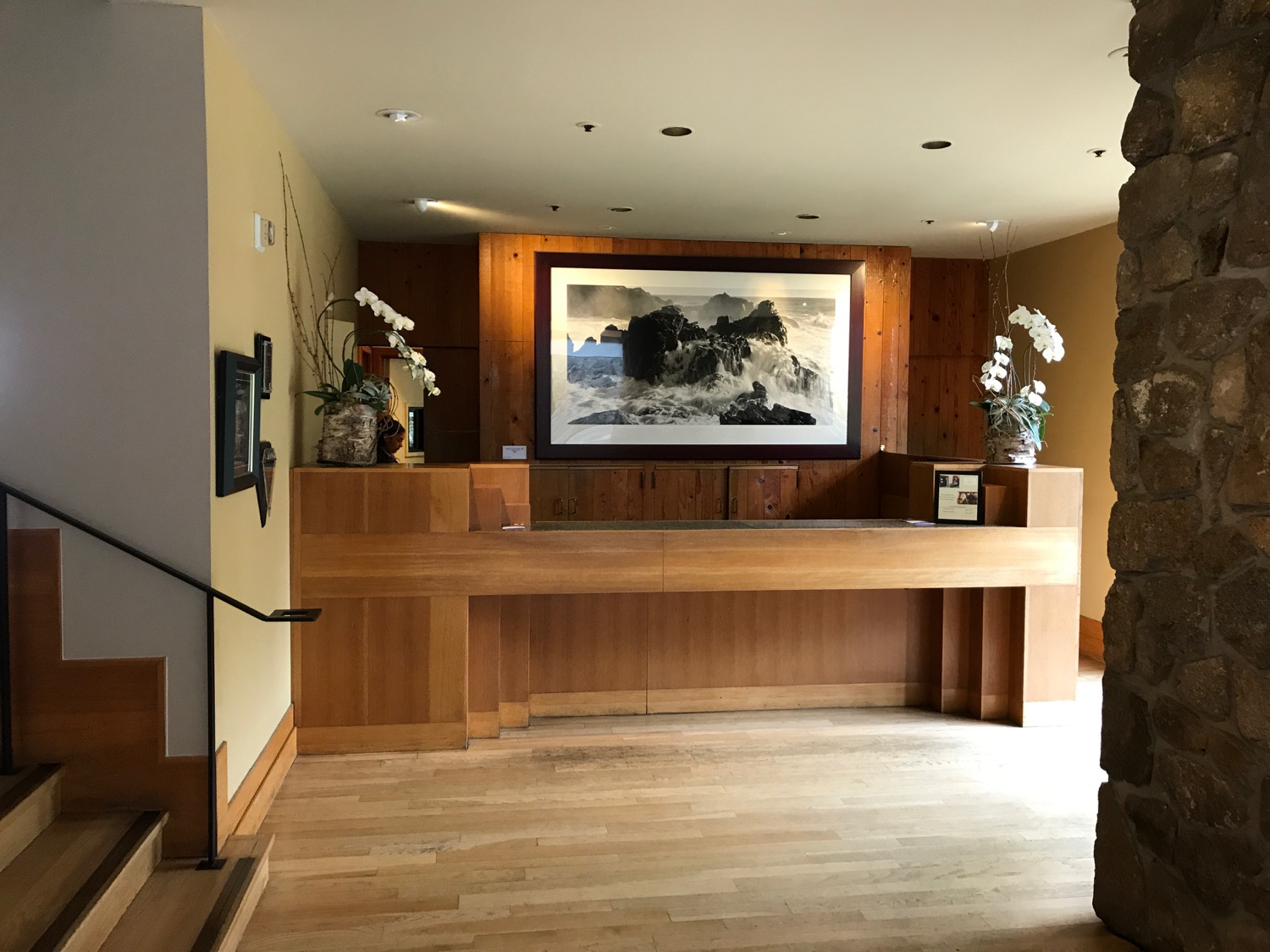 a wooden reception desk with a painting on the wall