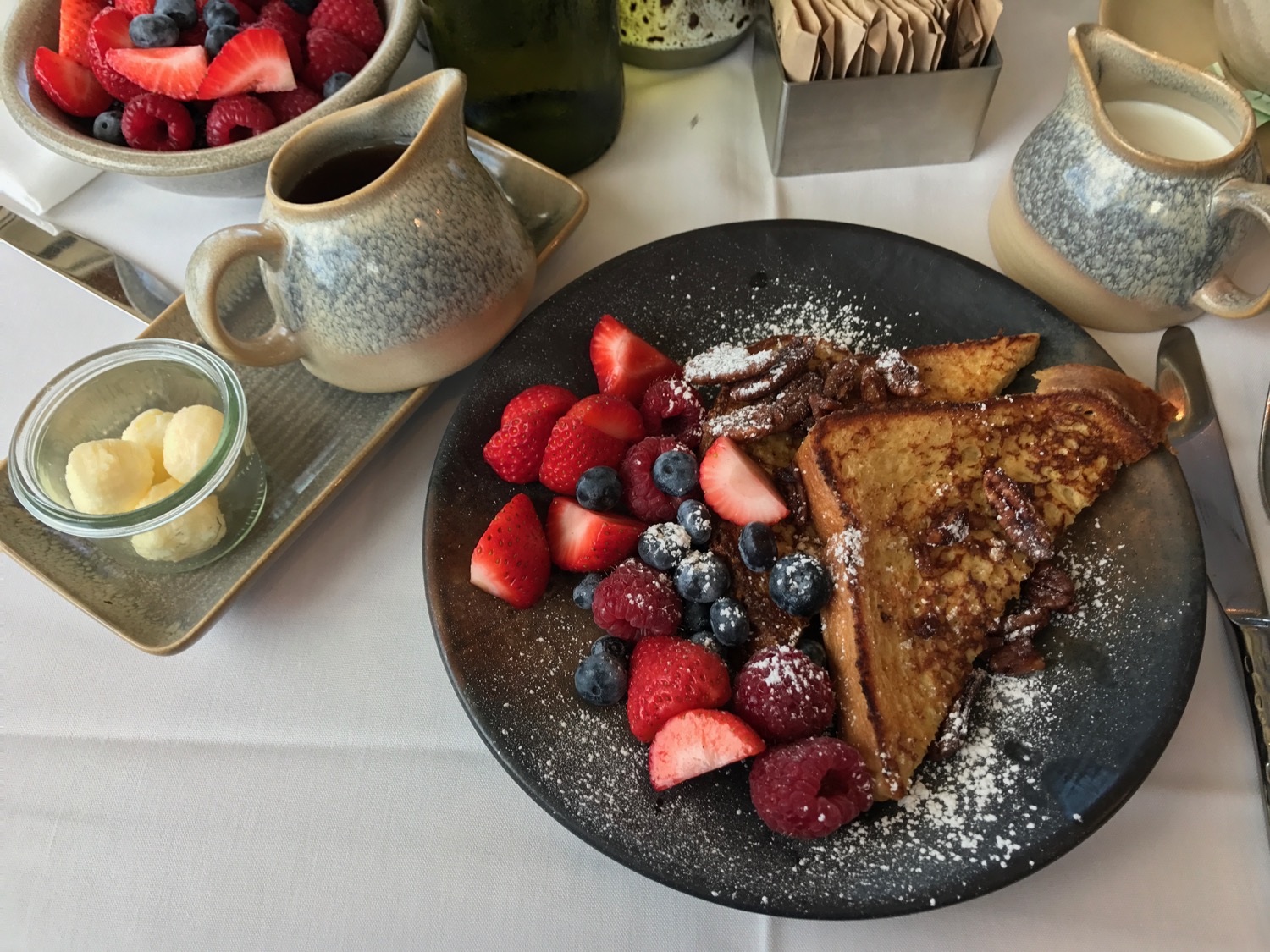 a plate of french toast with fruit and syrup