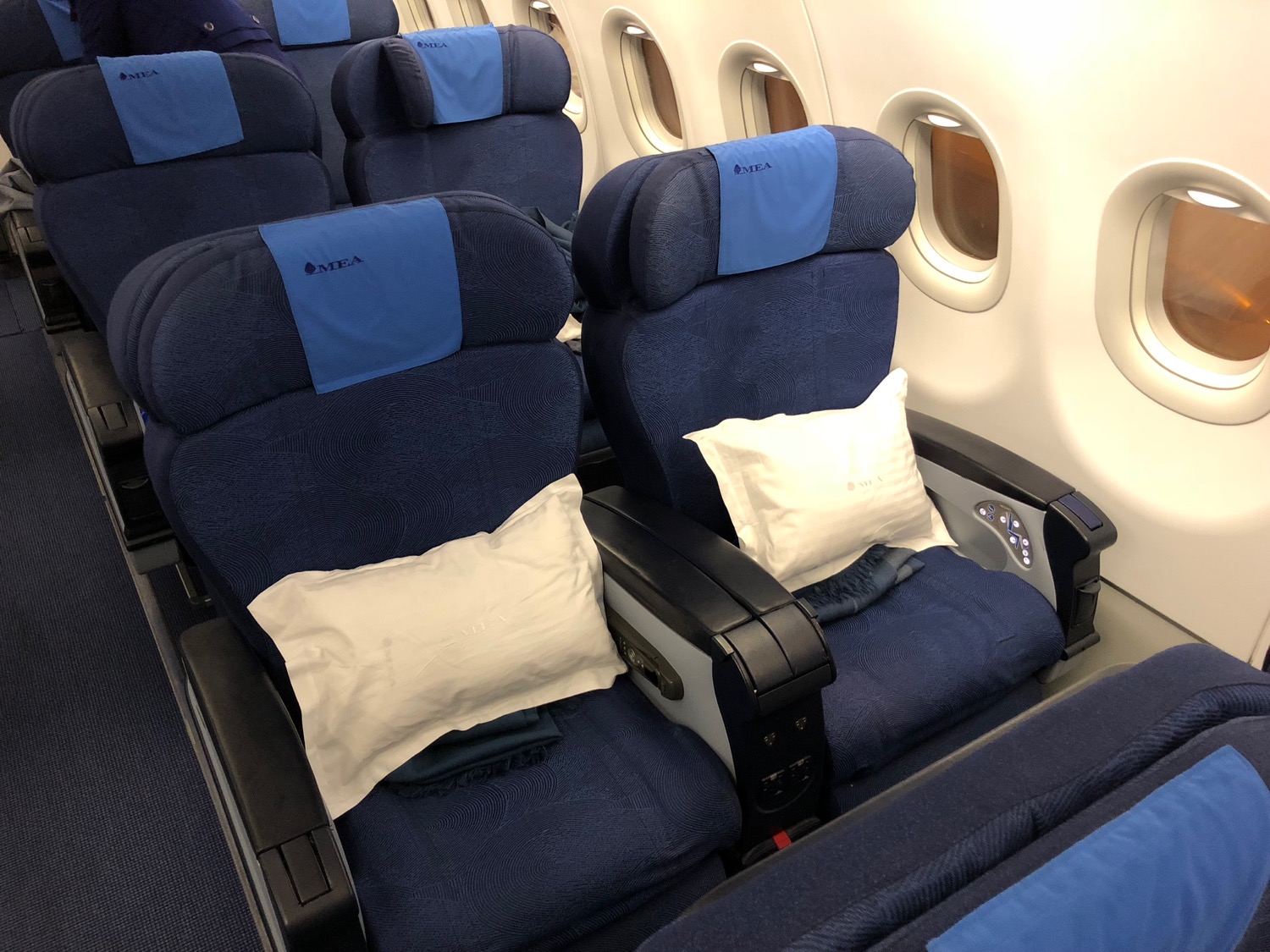 a row of blue chairs with white pillows on the side of the plane