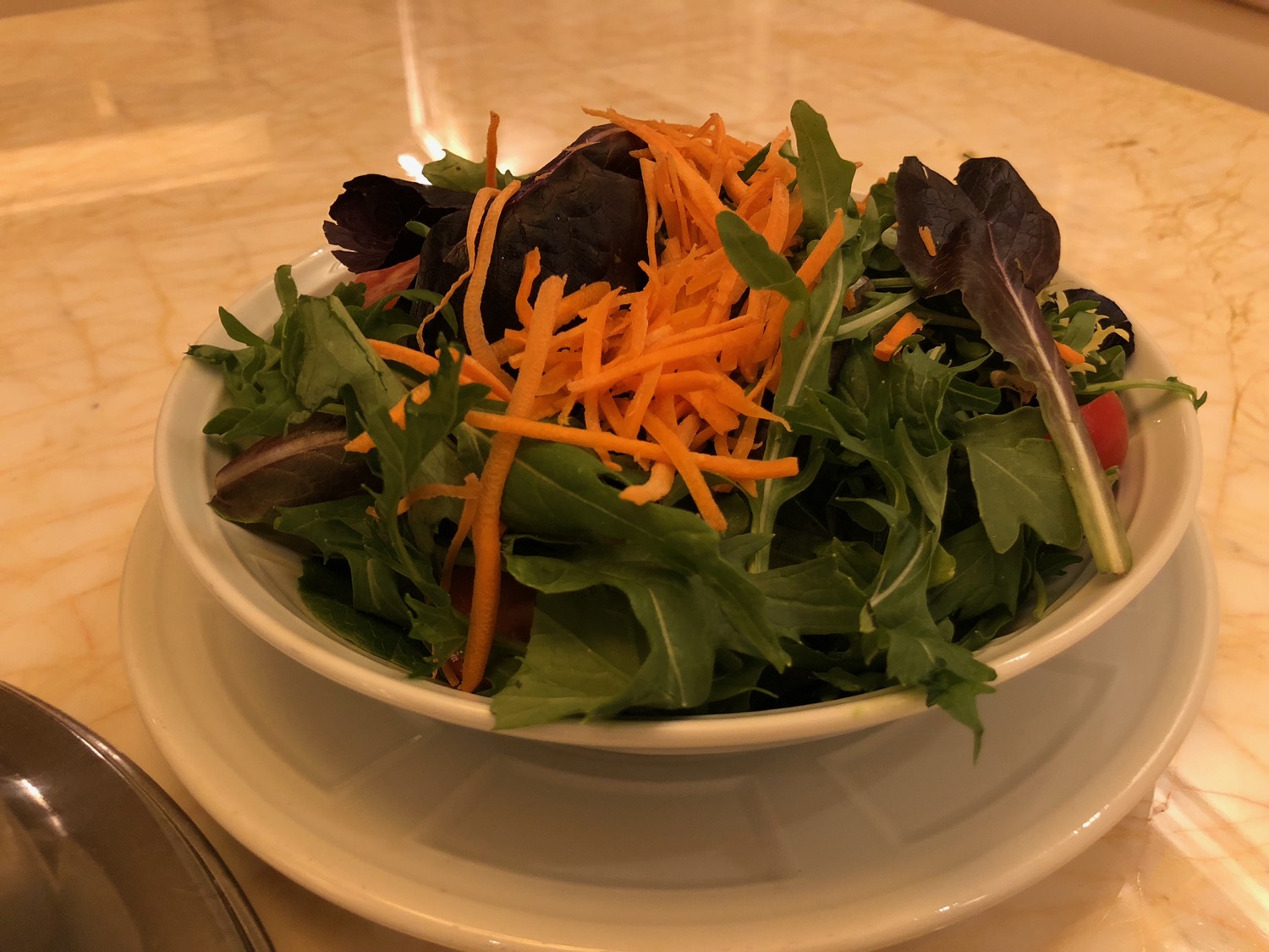 a bowl of salad with carrots and greens