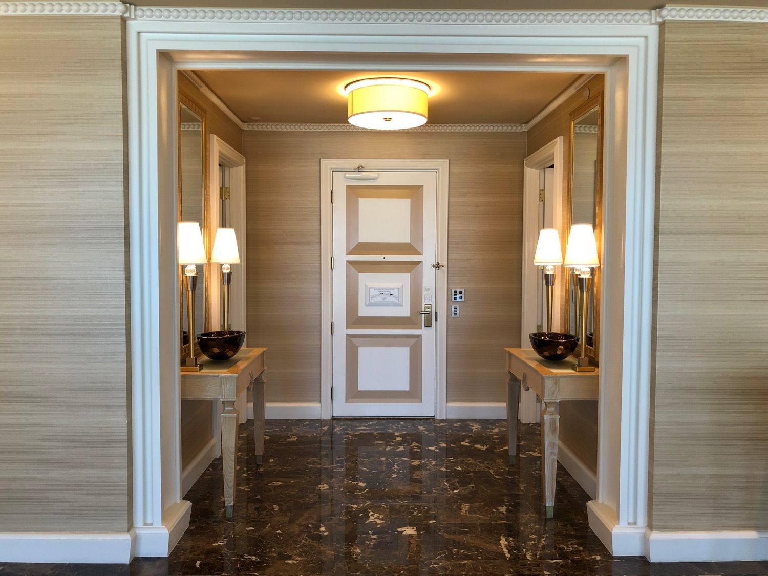 a hallway with a white door and two lamps