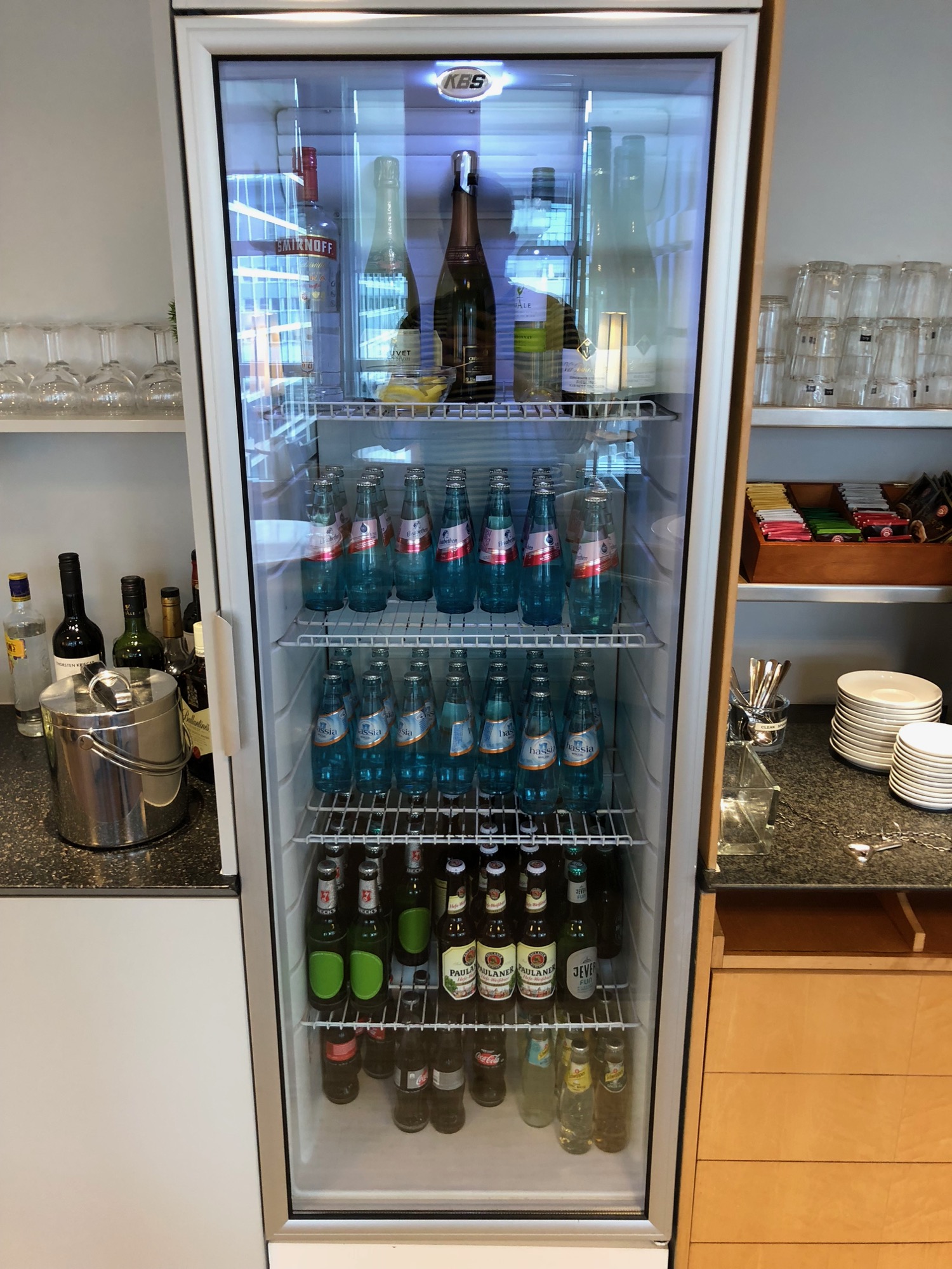 a refrigerator with bottles of soda and glasses