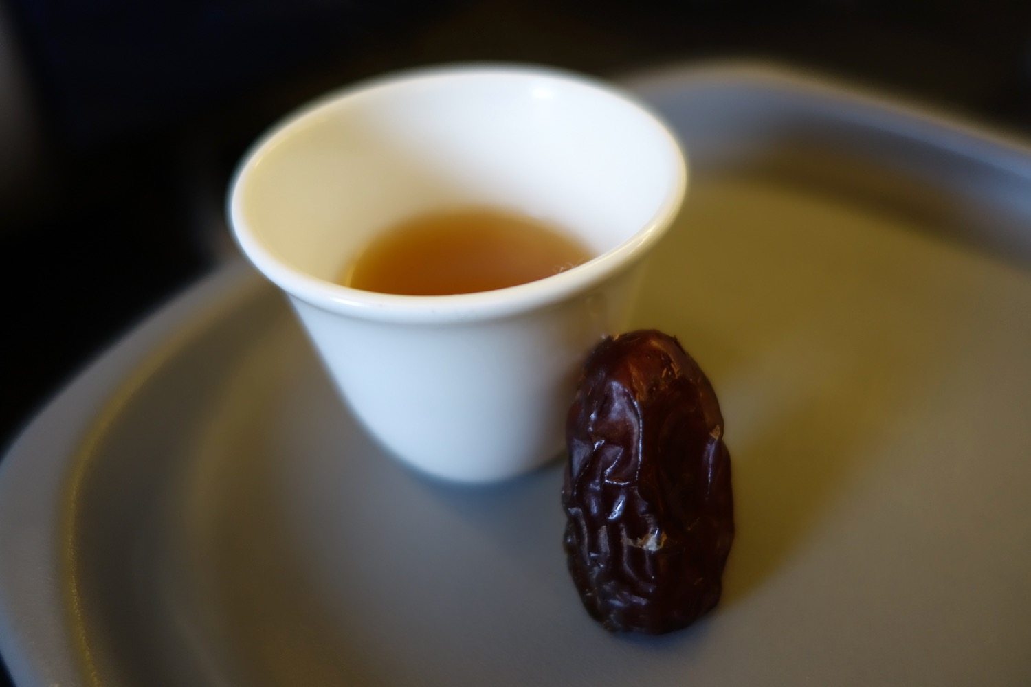 a small white cup with a brown liquid next to it