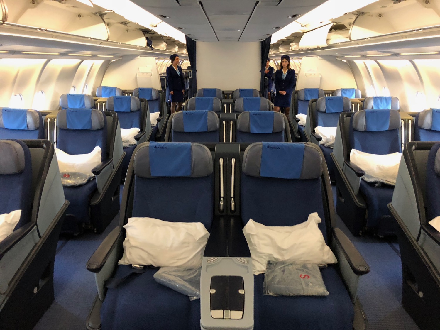 a plane with blue seats and people standing in the back