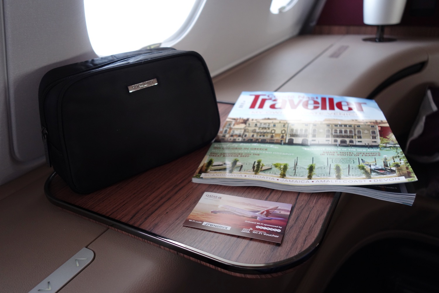 a magazine and a small black bag on a table in an airplane