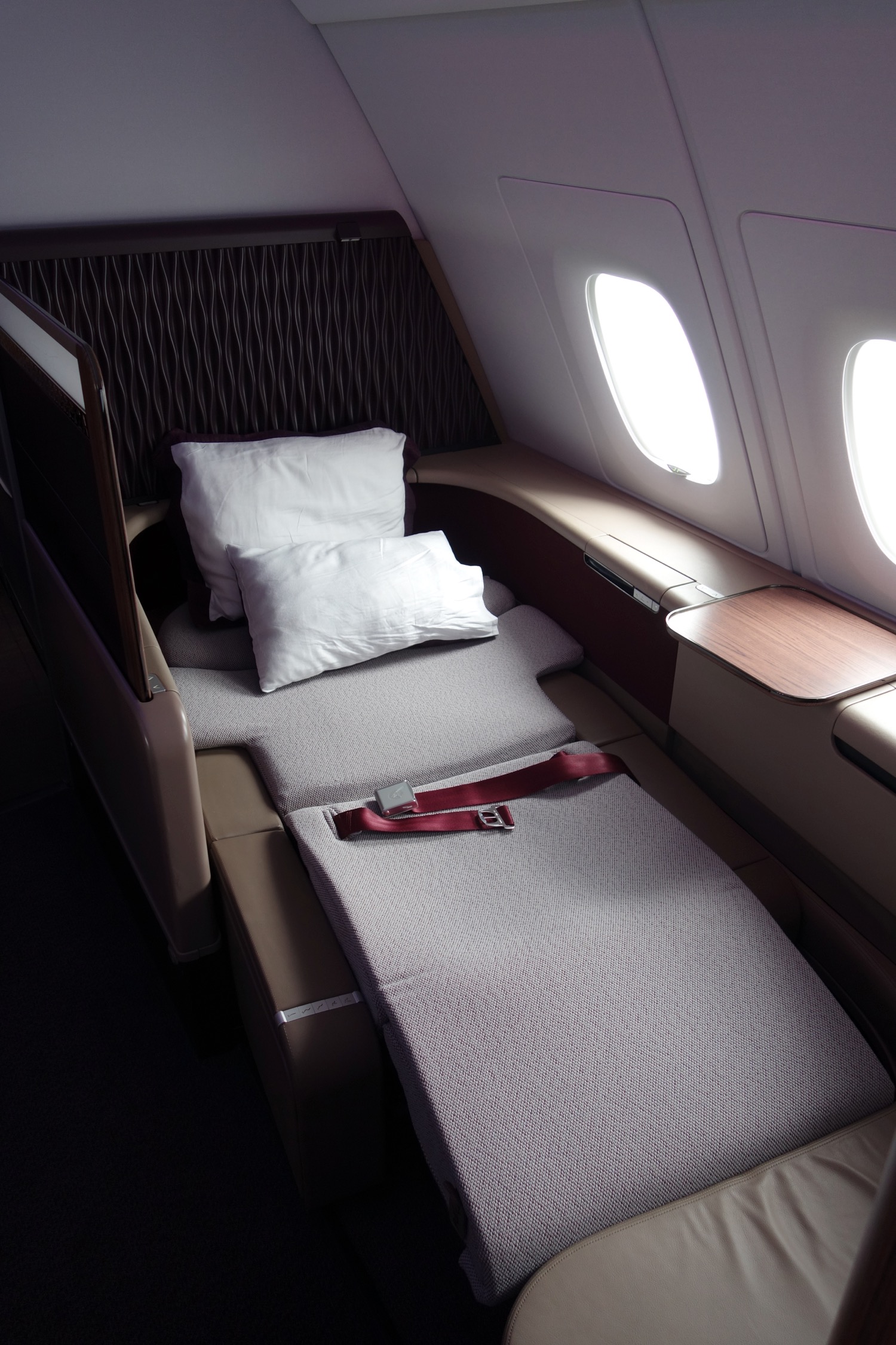 a seat belt and pillows on a bed in an airplane