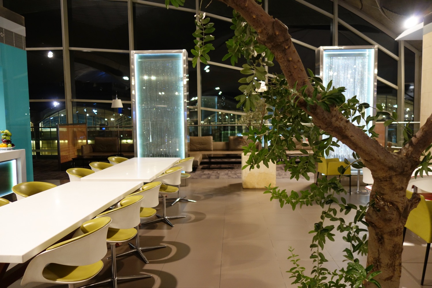 a tree in front of a white table with yellow chairs