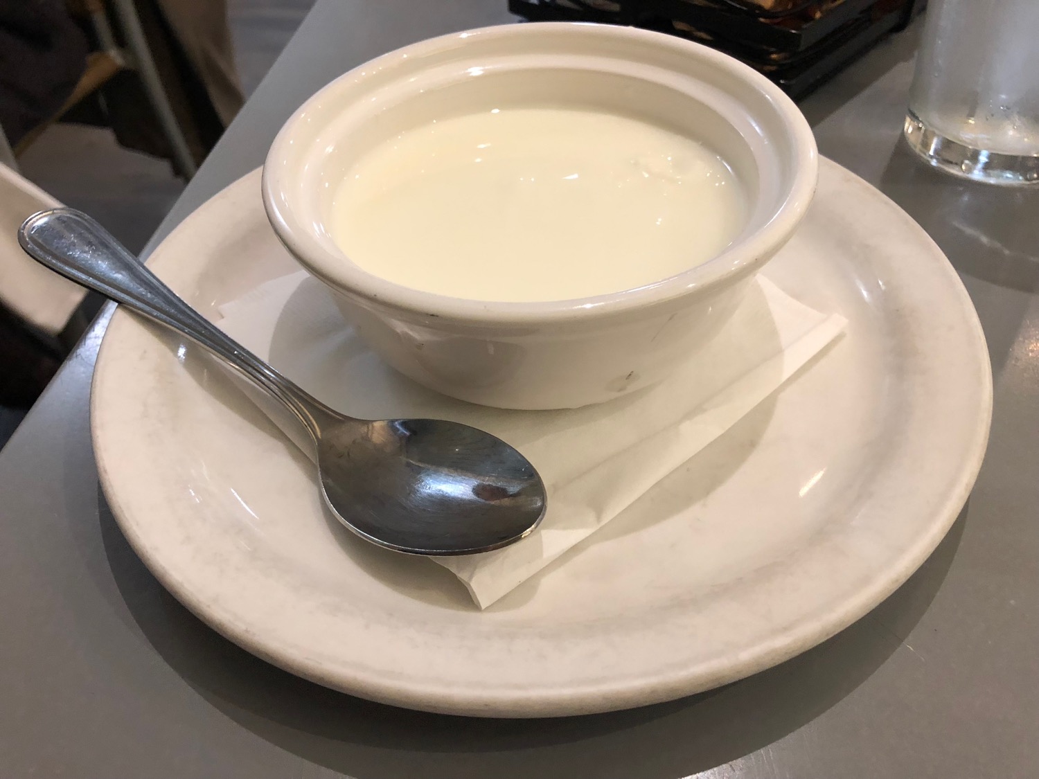 a bowl of milk on a plate with a spoon