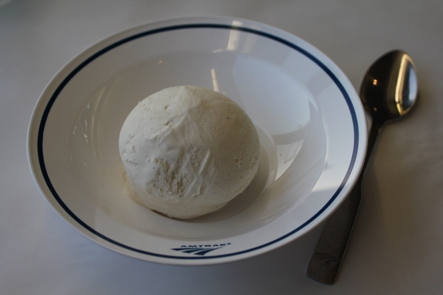 a white ball of ice cream on a white plate with blue trim