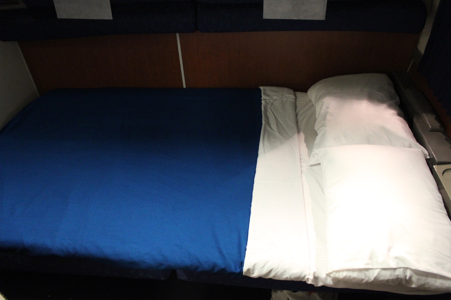 a bed with a blue sheet and white pillow