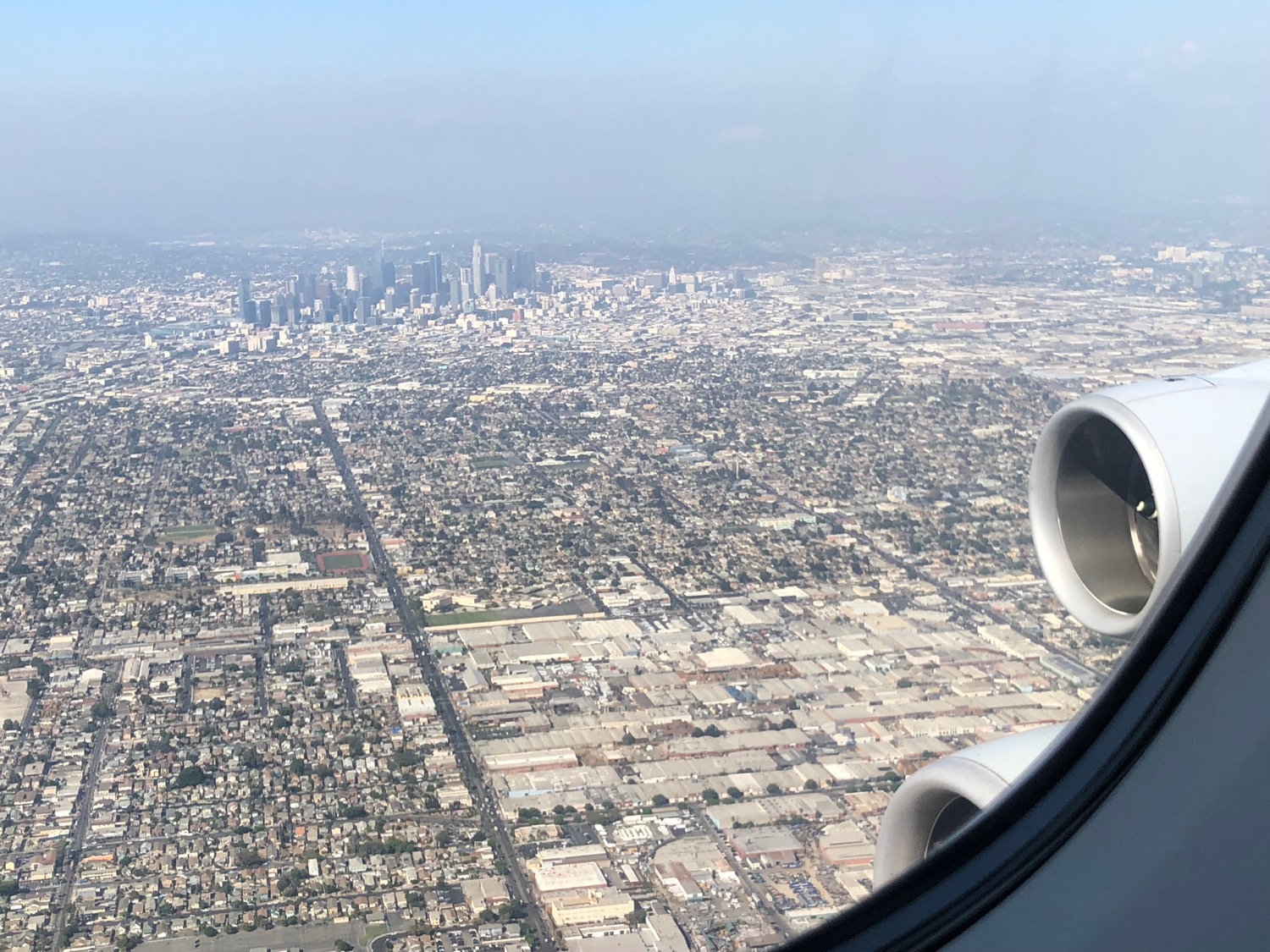 an airplane window with a city in the background