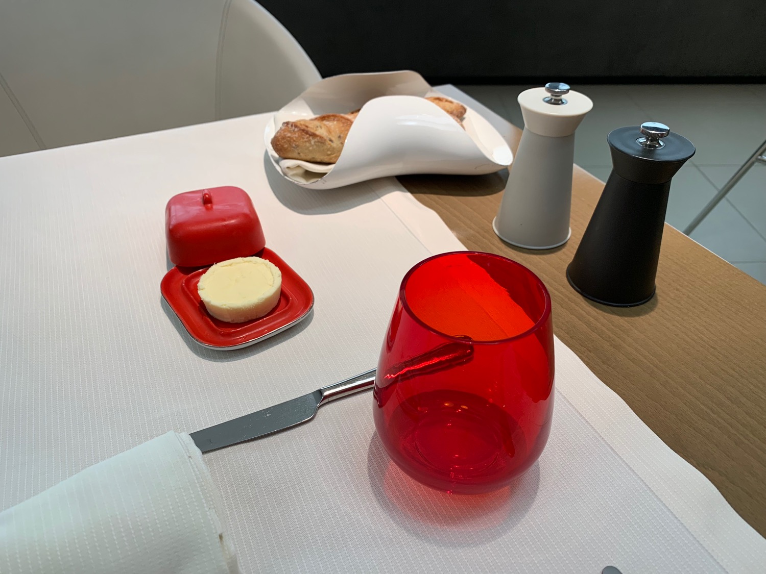 a red glass on a table with a knife and butter on it